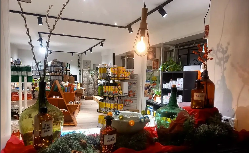 L'intérieur de la droguerie vu depuis la vitrine : étagères, flacons anciens et produits en vrac